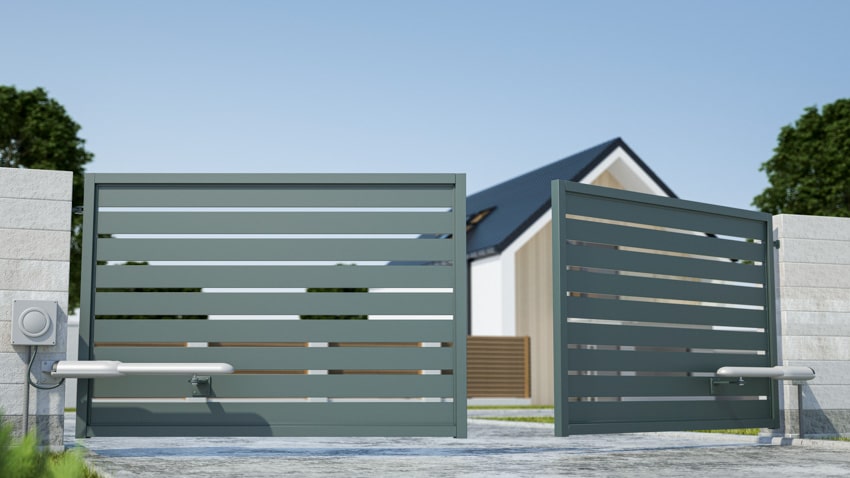 House exterior with metal swing driveway gate, wall, and pitched roof