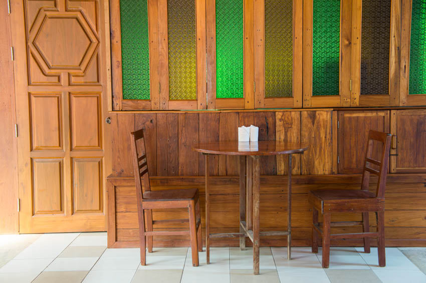 House interior with table and chair made of teak, wood door, and windows