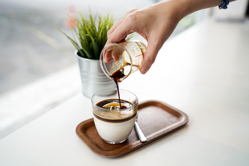 Individual pouring syrup on cup of coffee