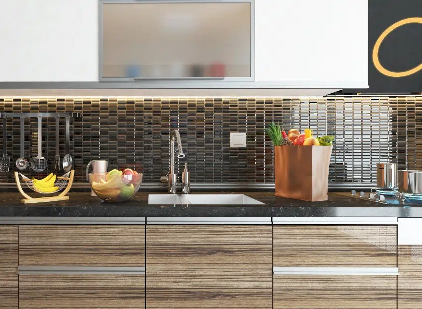 Kitchen counter with dark frosted glass, tile backsplash, sink and quartz countertop with a bag and bowl of fruits