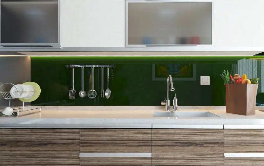 Kitchen counter with green frosted glass sheet backsplash, marble countertop with a bag of fruits and plates