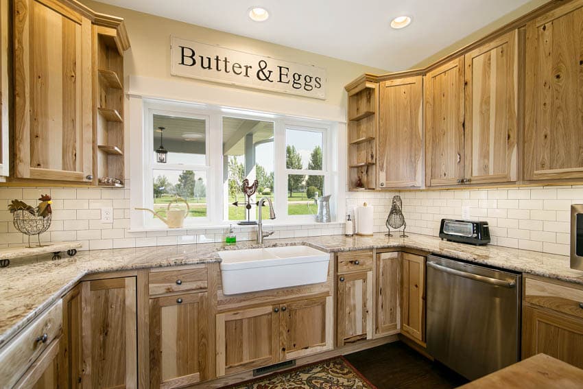 Kitchen with backsplash, countertop, sink, faucet, windows, and hickory cabinets