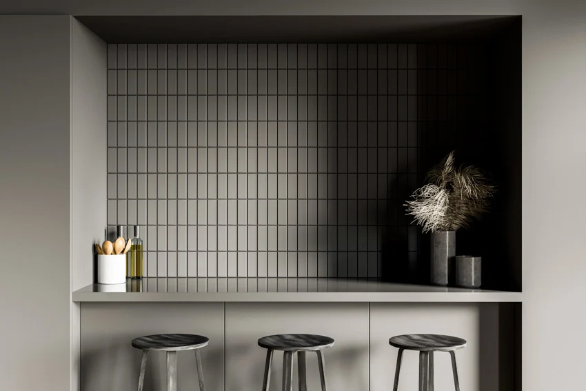 Kitchen with black kit kat tile backsplash, countertop, and stools