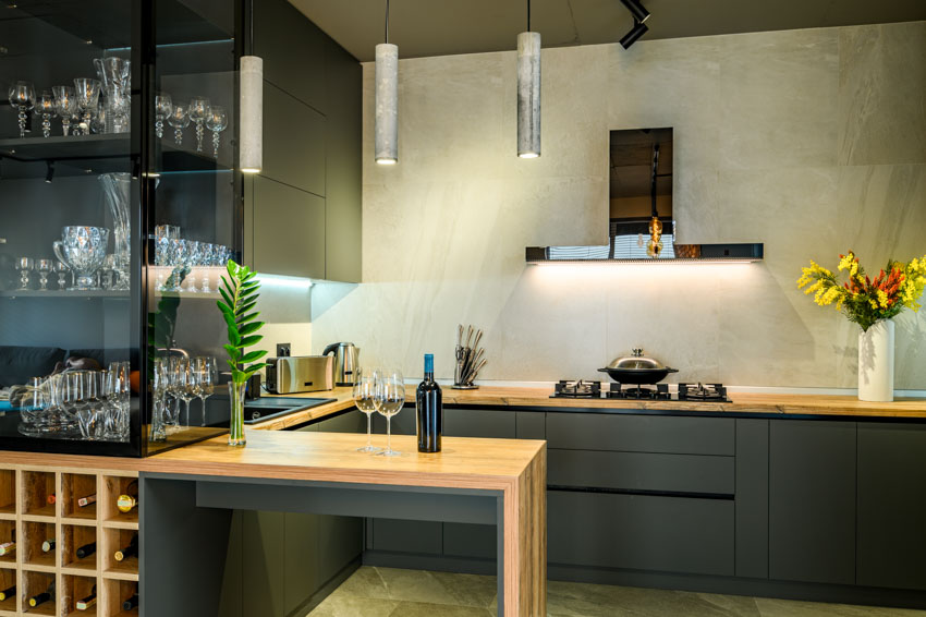 Kitchen with black matte cabinets, bar area, wine holder, wood countertop, range hood, and pendant lights