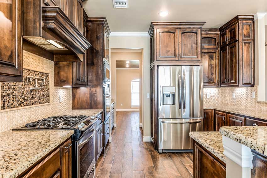 Kitchen with brown granite countertop, backsplash, wood cabinets, and wooden flooring