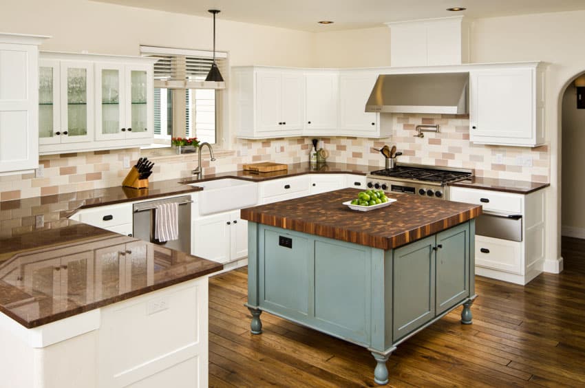 Kitchen with center island, built in cutting board, countertops, tile backsplash, cabinets, stove, and range hood