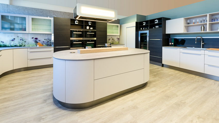 Kitchen with center island, curved cabinets, wood floor, refrigerator, backsplash, faucet, and countertops