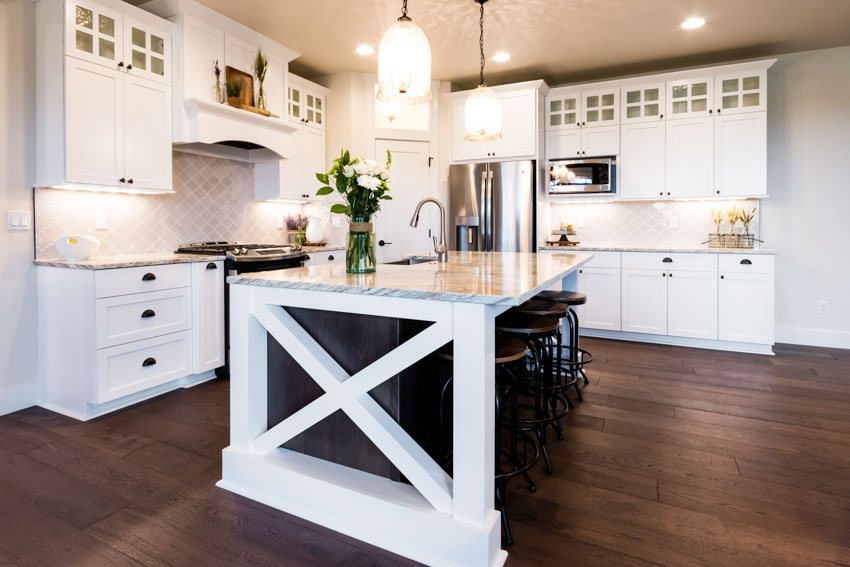 Kitchen with center island, wood floors, granite countertops, backsplash, pendant lights, and cabinets