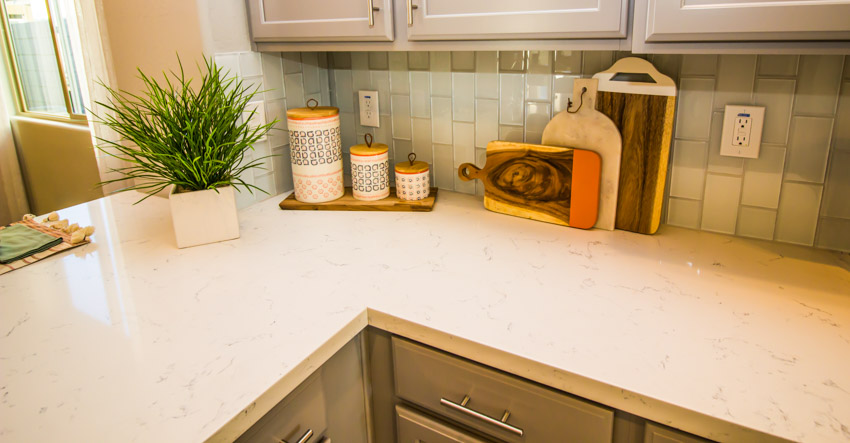 Countertop with potted plant, three jars and white cupboards