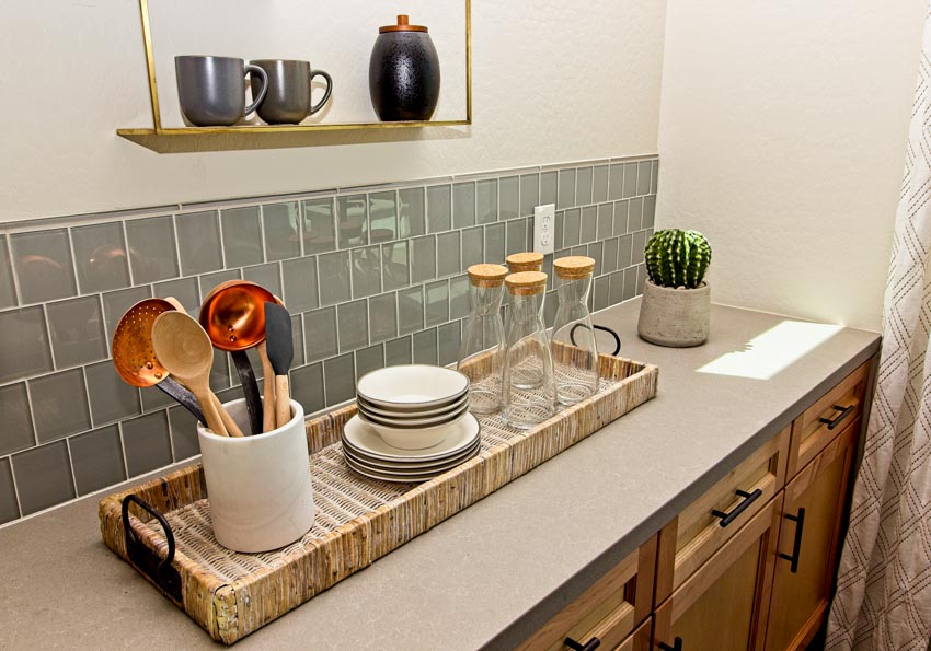 Kitchen with countertop, wood cabinets, hanging shelf, and glass subway tile backsplash