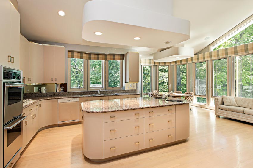 Kitchen with curved cabinets, center island, drawers, windows, ceiling lights, wood floors, oven, and countertop