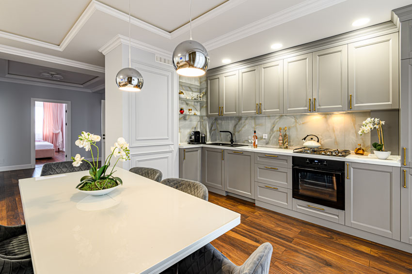 Kitchen with dining area, table, cabinets, backsplash, and pendant lights