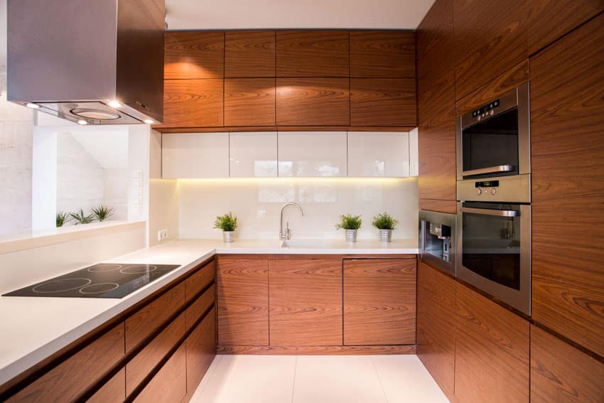 Kitchen with frameless cabinet doors made of wood, countertops, induction stove, range hood, stove, and faucet