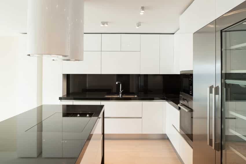 Kitchen with frameless cabinets, countertops, backsplash, range hood, and induction stove