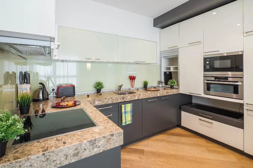 Kitchen with frosted glass sheet backsplash, white cabinets, built in double oven and plants and food on countertop