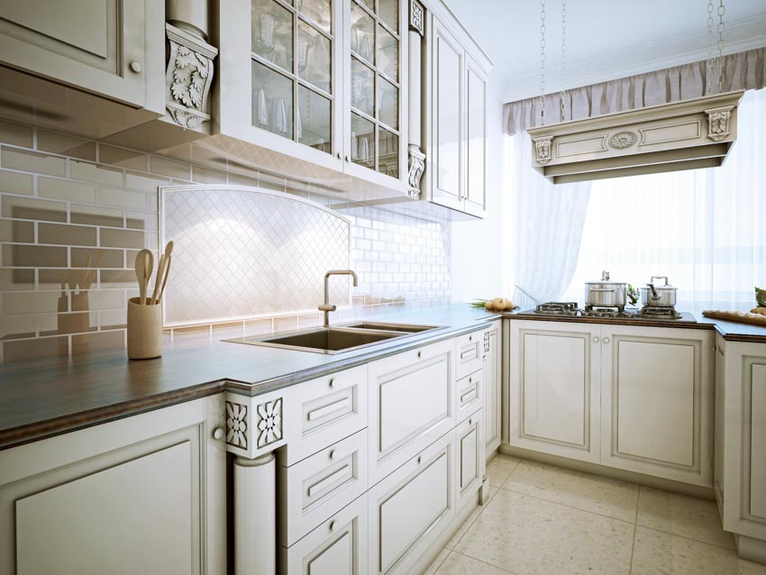 Kitchen with glass subway tile backsplash, cabinets, drawers, countertop, and window