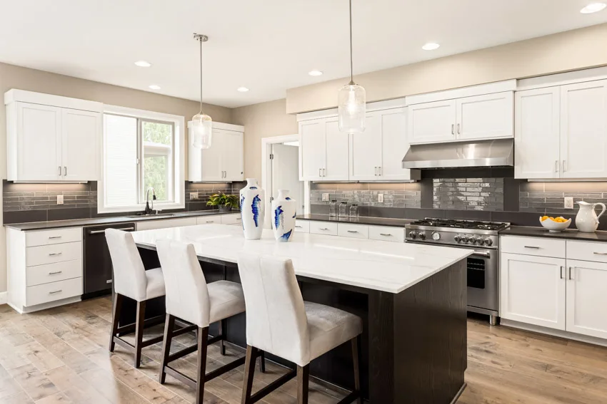 Kitchen with white dining chairs, black countertop and flat paneled cabinets