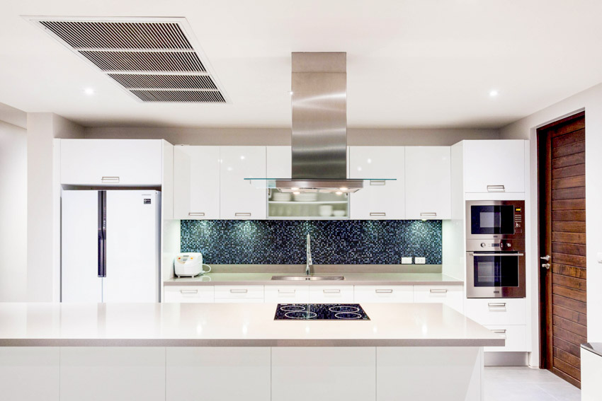 Kitchen with granite countertops, tile backsplash, island, sink, range hood, cabinets, wood door, and refrigerator