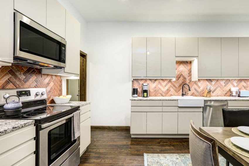 Kitchen with herringbone wood tile backsplash, flat panel cabinets, countertops, oven, stove, and wood floors