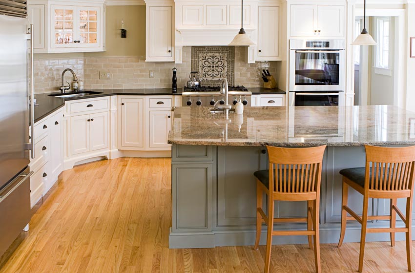 Kitchen with island, granite countertops, backsplash, high chairs, white cabinets, and wood flooring