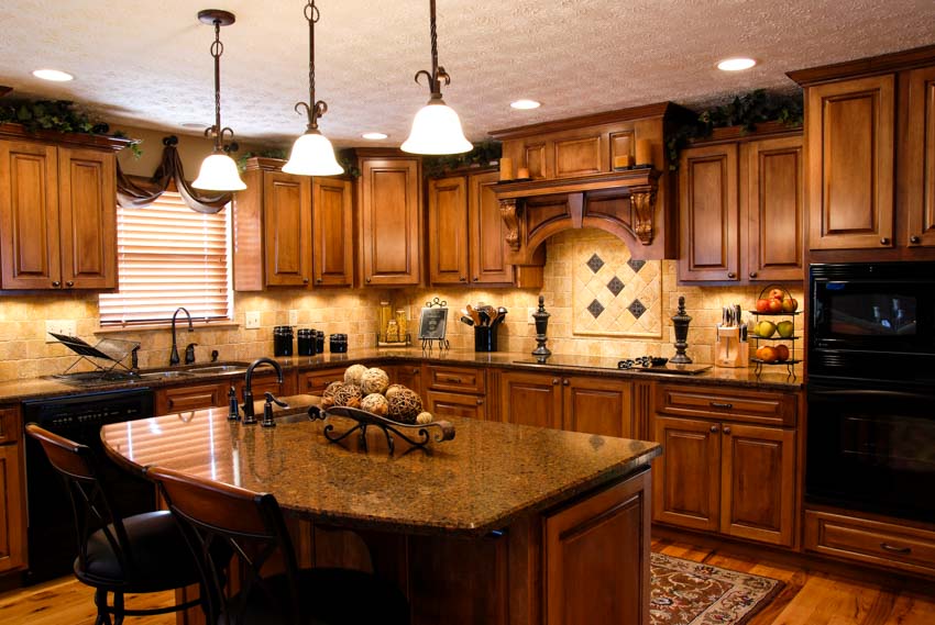 Kitchen with limestone brick veneer backsplash, wood cabinets, island, chairs, pendant lights, countertop, and window