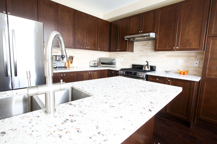 Kitchen with limestone subway tile backsplash, granite countertop, sink, faucet, stove, range hood, and refrigerator
