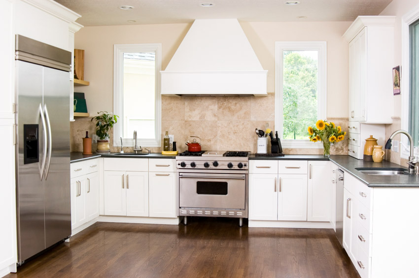 U-shaped kitchen with panel windows, white hood and black countertop 