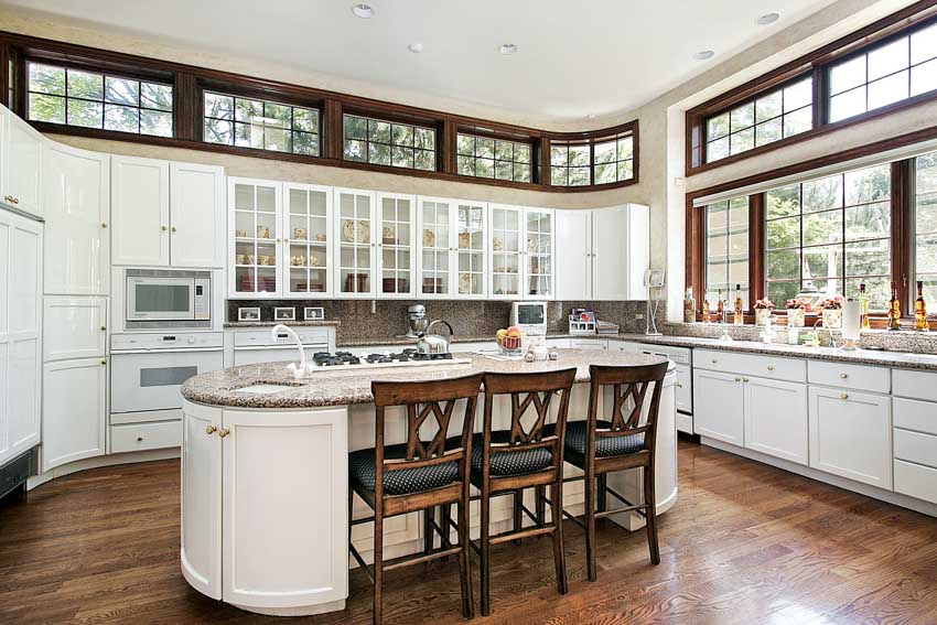Kitchen with peninsula, curved cabinets, chairs, windows, backsplash, countertops, windows, and wood floors