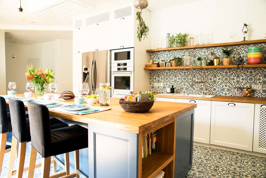 Kitchen with peninsula, wood shelves, countertops, chairs, backsplash, and patterned floors