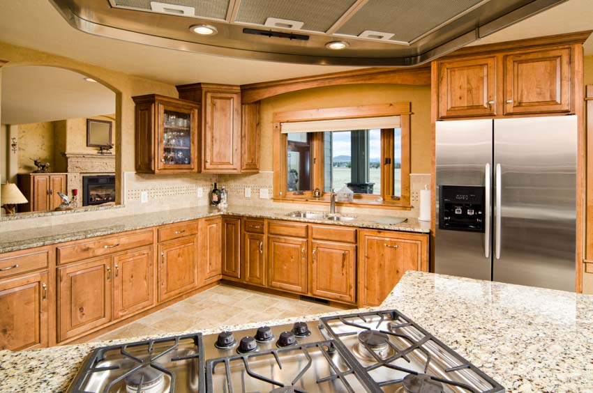 Kitchen with refrigerator, granite countertops, stove, window, and red oak cabinets
