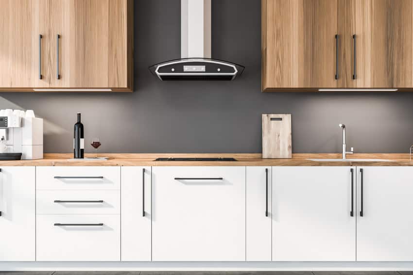 Kitchen with veneer cabinets, wood countertop, and grey backsplash