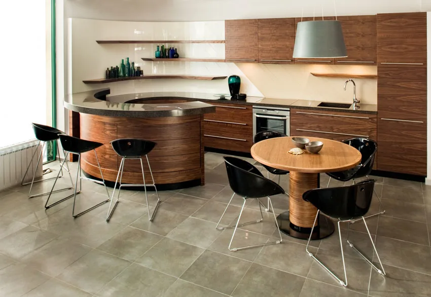 Kitchenw ith natural stone flooring. floating shelves and black chairs
