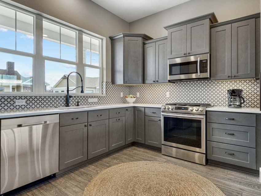 Kitchen with tile backsplash, oven, window, and MDF cabinets