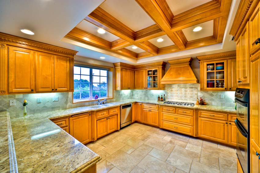 Kitchen with boxed ceiling, travertine floors and dark yellow cabinets