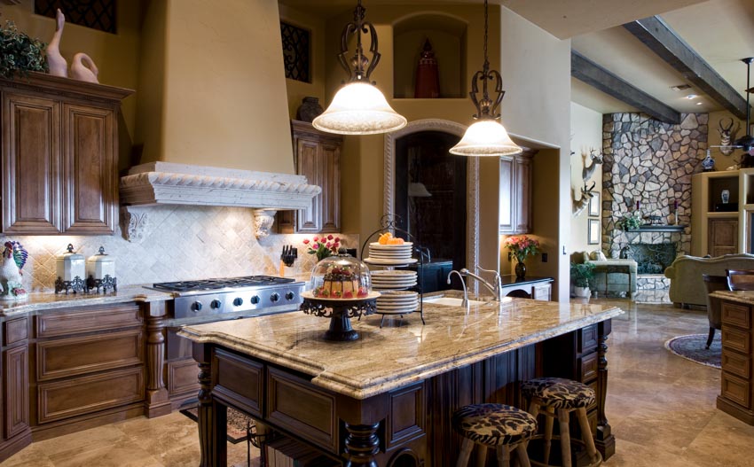 Mediterranean style kitchen with large hood, stone accent wall and upholstered stools