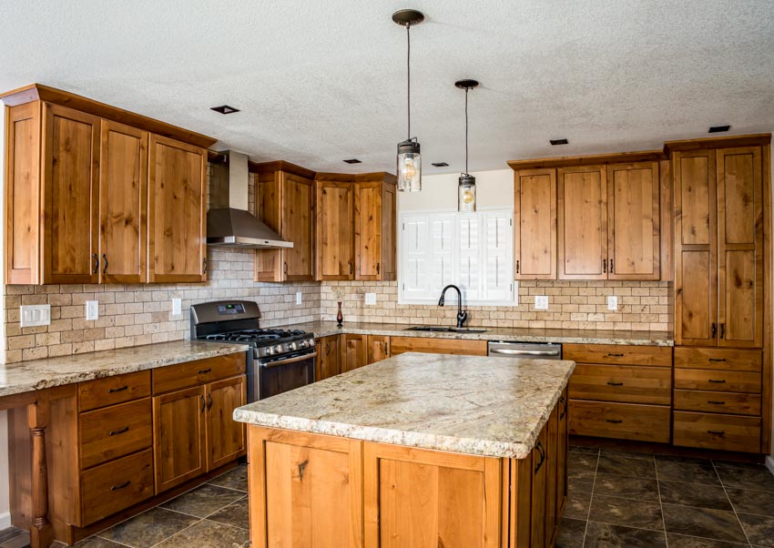 Kitchen with wood cabinets, limestone tile backsplash, countertops, island, pendant lights, tile floors, and range hood