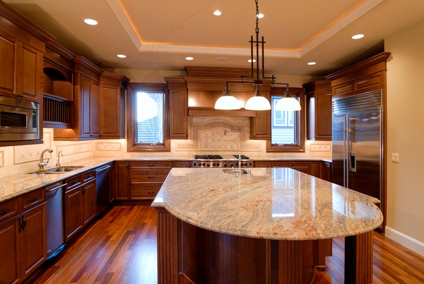 Kitchen with wood floors, center island, granite countertop, limestone backsplash, cabinets, and pendant lights