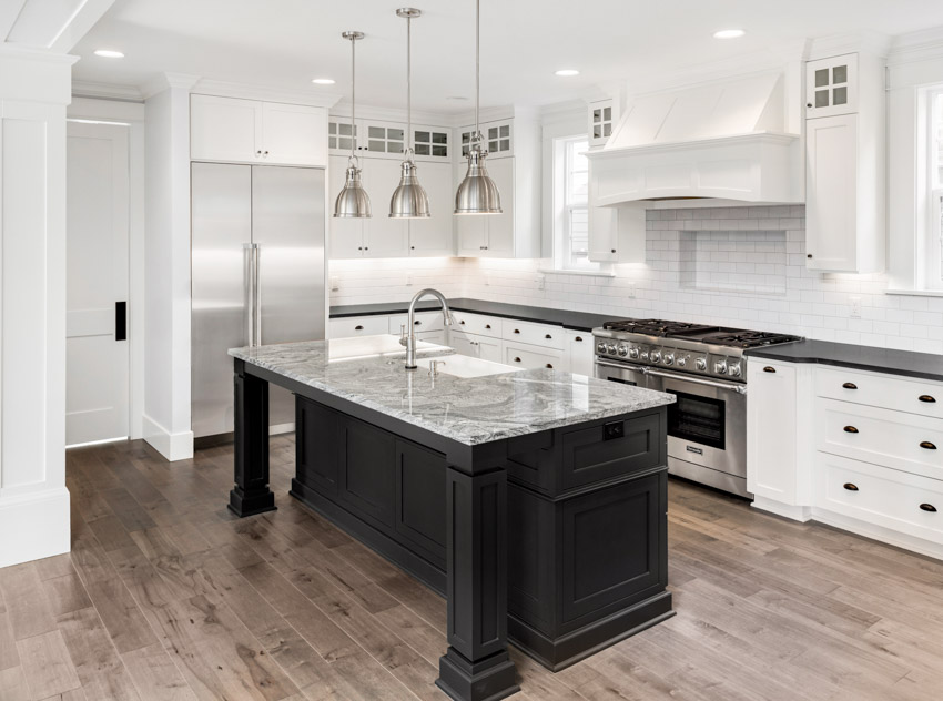 Kitchen with wood floors, island, granite countertops, subway tile backsplash, white cabinets, drawers, and pendant lights