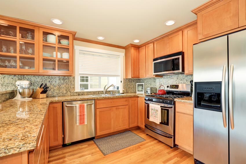 Kitchen with wood floors, mat, ceiling lights, countertops, oven, refrigerator, red oak cabinets, and window