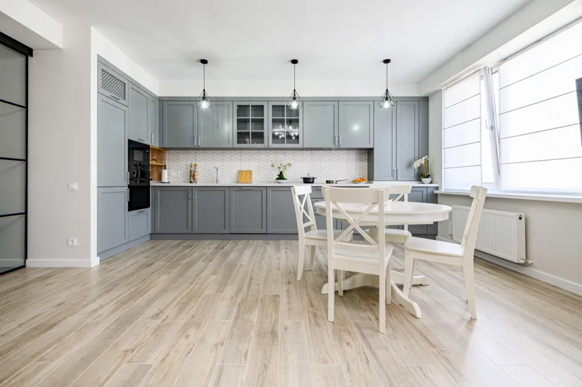 Kitchen with chevron tile backsplash, gray cabinets, and pendant lights
