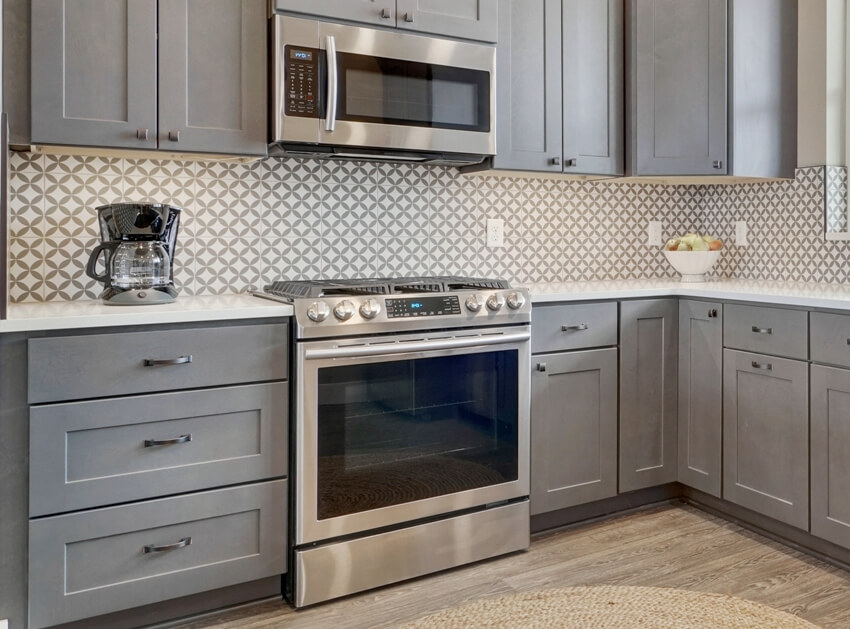 Kitchen vinyl floors, dark grey cabinets, slide in oven range and microwave on top