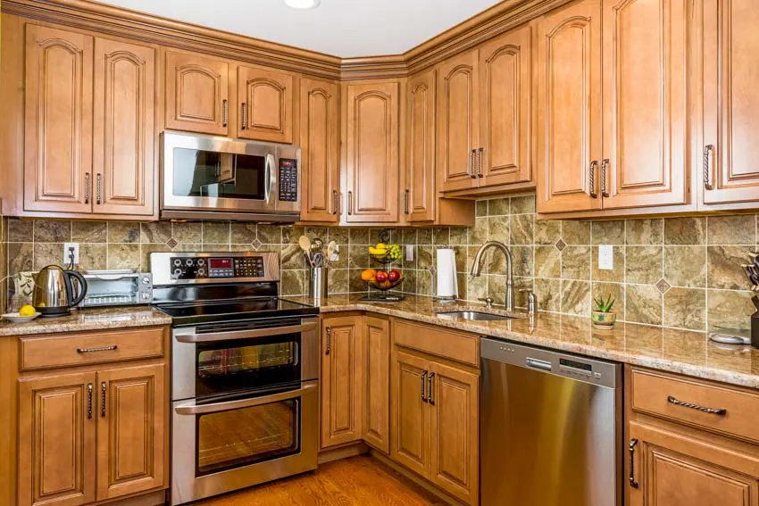 Kitchen wth tile backsplash, countertops, oven, stove, and red oak cabinets