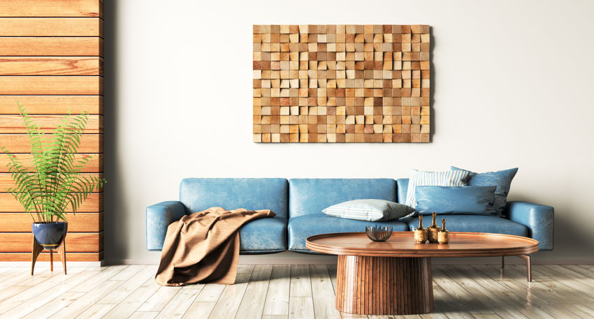 Living room with blue leather sofa, wood accent wall, coffee table, indoor plant, and pillows