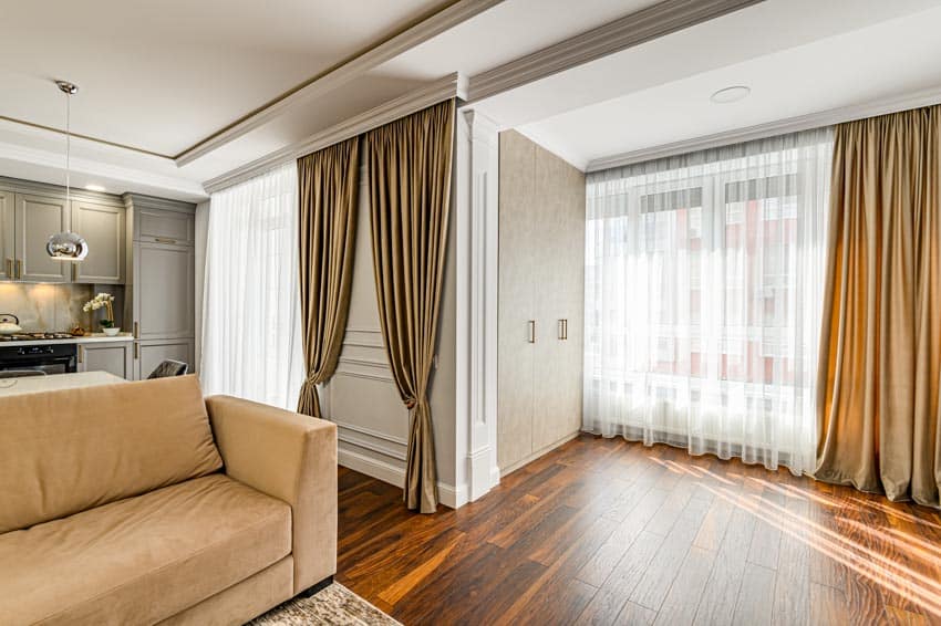 Living room with cushioned sofa, motorized curtains, and wood floors