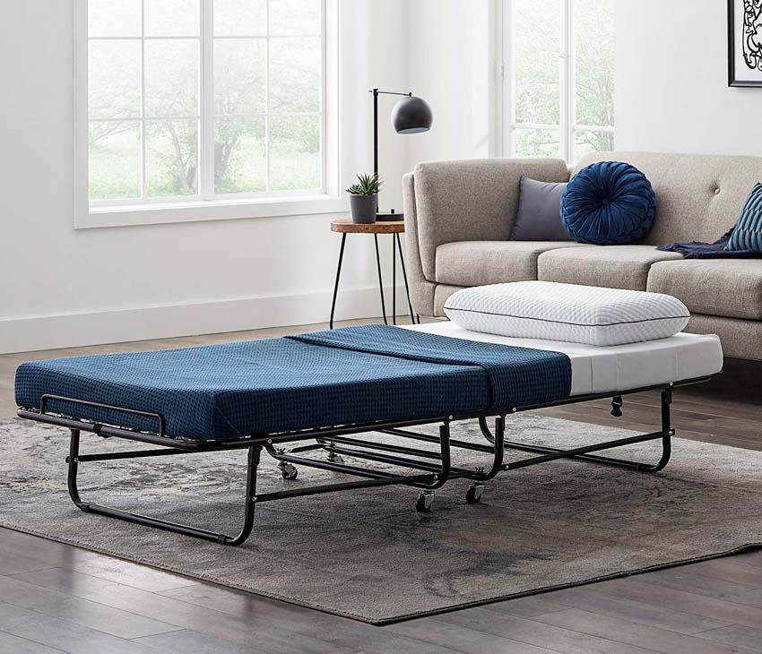 A blue folding bed with white pillow and gray rug