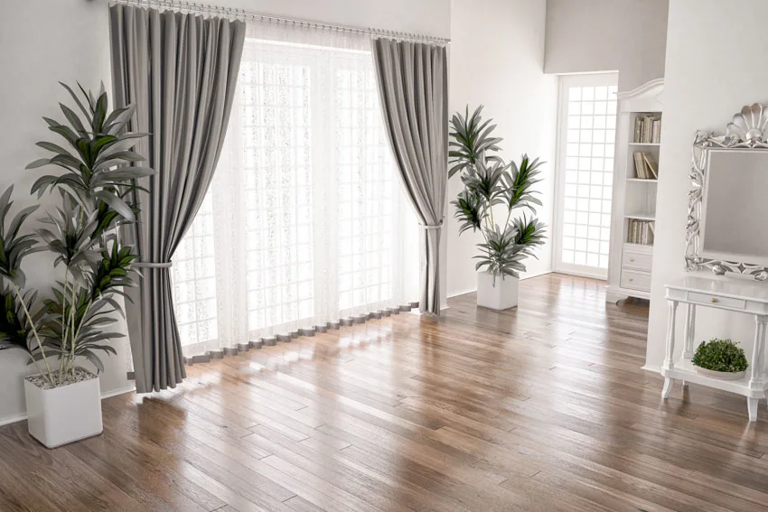 Living room with polished wood floors, mirror, and grey curtains