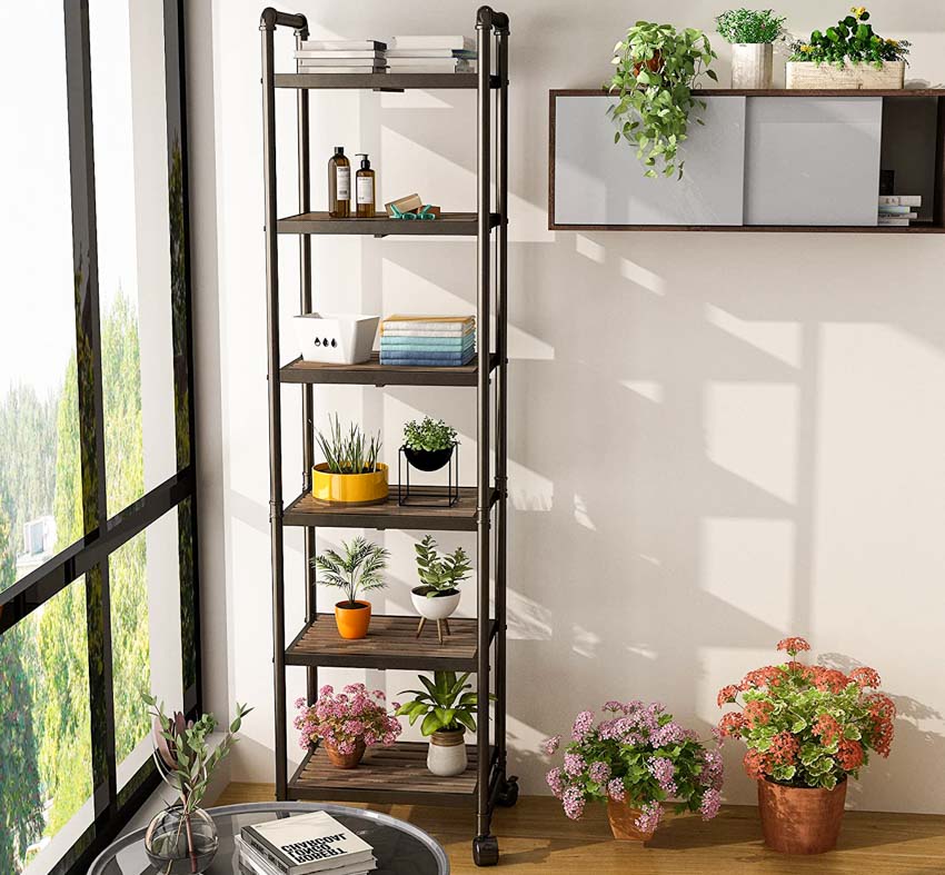 Living room with rolling shelf, wood floor, potted plants, and flowers