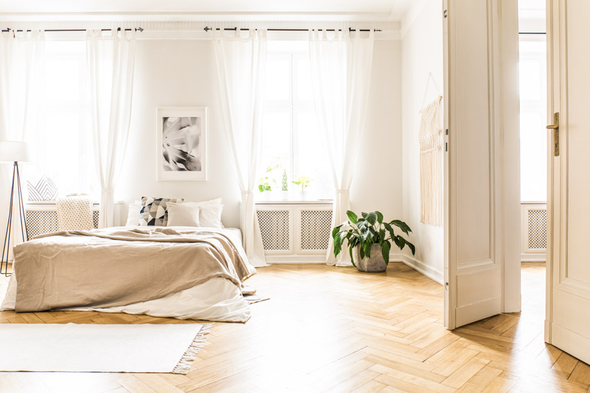 White curtains, herringbone style floors and tall white doors
