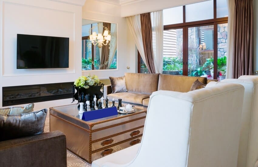 Living room with sofas, center table, wall mounted tv and layered curtains on big windows