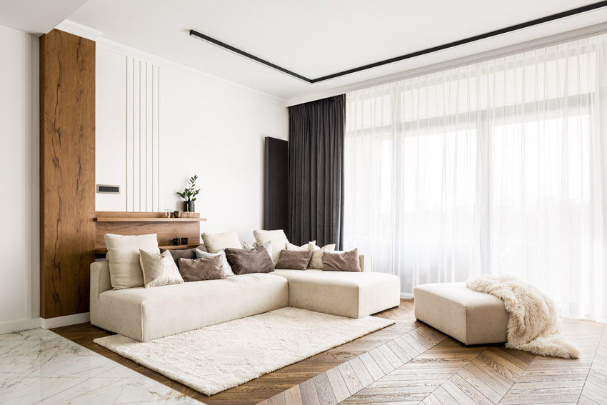 Room with walnut shelf, sectional sofa, ottoman, rug and wood floor